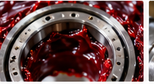 Red industrial grease packed into a bearing